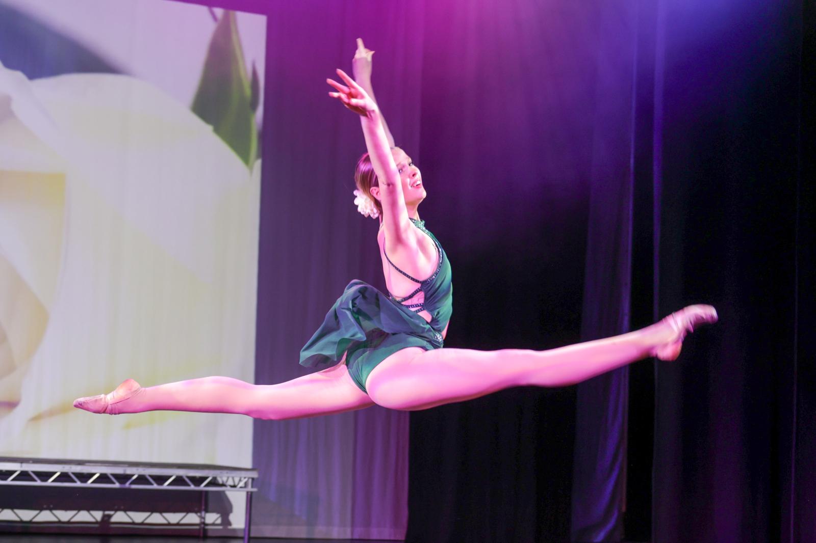 A T's Studios dancer performing a leap on stage