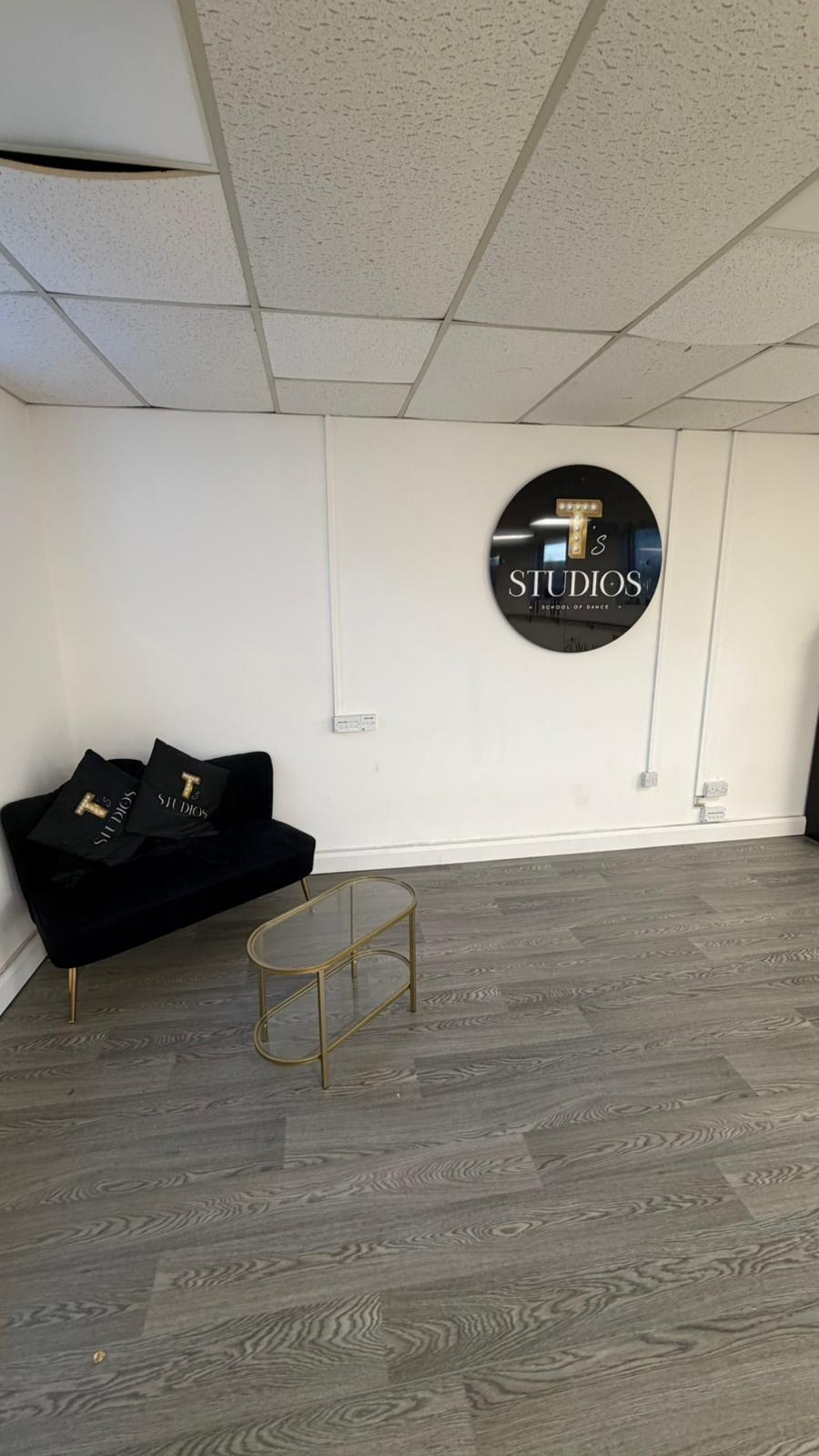 Reception area with sofa and round T's Studios logo sign